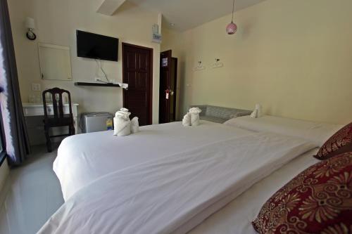 two white beds with stuffed animals on top of them at Baan Pordeedin in Chiang Rai