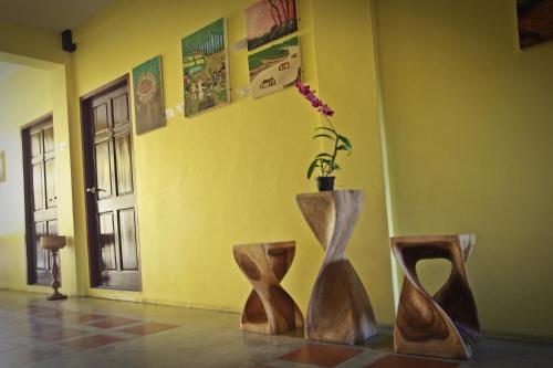 a room with two wooden vases and a yellow wall at Baan Pordeedin in Chiang Rai