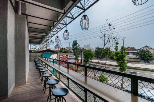 a row of stools on a balcony with a view at Maple Hotel Grogol in Jakarta