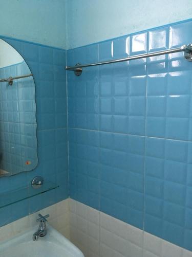 チェンライにあるSubrangsee Apartmentの青いタイル張りのバスルーム(シンク、鏡付)