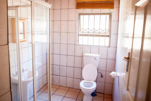 a bathroom with a toilet and a sink and a window at Oria Lodge in Cape Town