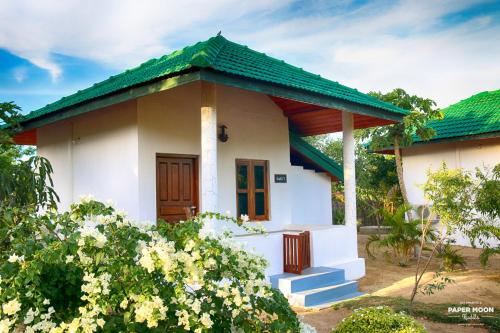 a small white house with a green roof at Paper Moon Kudils in Arugam Bay