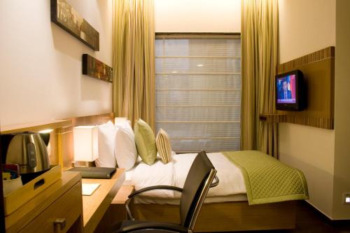 a hotel room with a bed and a desk with a television at Shervani Nehru Place in New Delhi