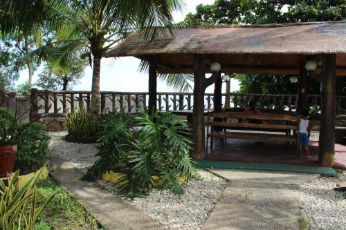 a wooden pavilion with a bench in a garden at Lagnason's Place in Oslob