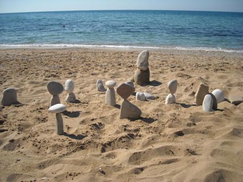 a group of stone figures in the sand on a beach at Kostas Apartments & studios in Agios Georgios Pagon