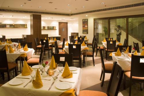 un restaurante con mesas y sillas con servilletas amarillas. en Shervani Nehru Place, en Nueva Delhi
