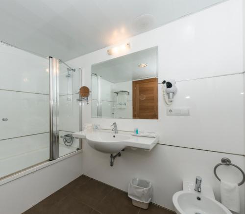 a white bathroom with a sink and a mirror at Hotel Portocobo in Santa Cruz de Oleiros