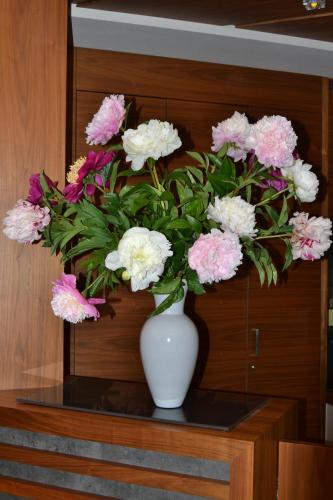 a white vase filled with pink and white flowers on a table at Alagundis Apartment Residence in Lagundo