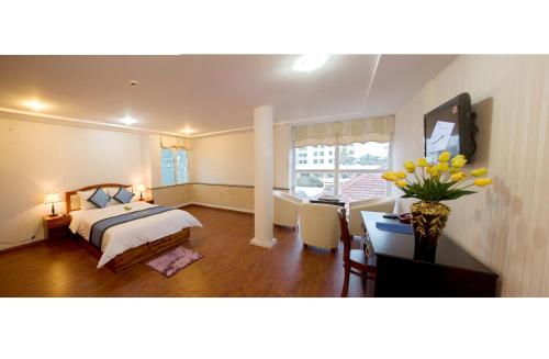 a bedroom with a bed and a table with a vase of flowers at Song Thu hotel in Da Nang