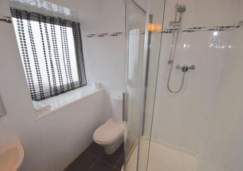 a white bathroom with a toilet and a shower at Armadale Cottage in Lochgoilhead