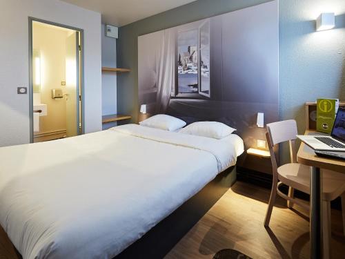 een slaapkamer met een bed en een bureau met een laptop bij B&B HOTEL Cherbourg in Cherbourg en Cotentin