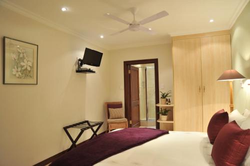 a bedroom with a bed with a ceiling fan at Claires of Sandton Luxury Guest House in Johannesburg