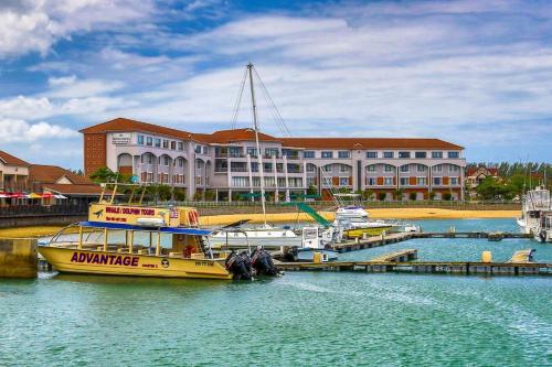 a yellow boat is docked in the water in front of a building at La Rochelle Inn in Richards Bay
