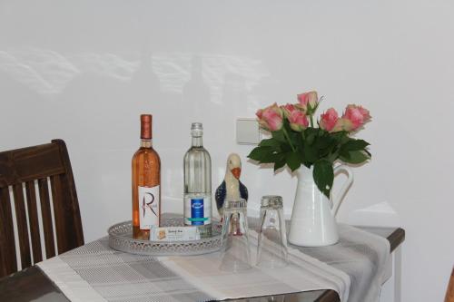 a table with wine bottles and a vase with flowers at MariaPrimaVera Apartment am Kurpark mit Schwarzwaldblick * * * * in Bad Krozingen
