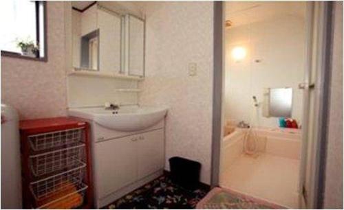 ein Badezimmer mit einem Waschbecken und einer Badewanne mit einem Waschbecken in der Unterkunft Youyousanso Traditional B in Tsu