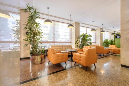 a waiting room with orange chairs and a table at Hotel Reytan in Warsaw