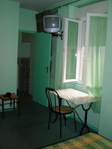 a room with a table and a tv and a window at Hotel Restaurant du Lion d'Or in Château-Chinon