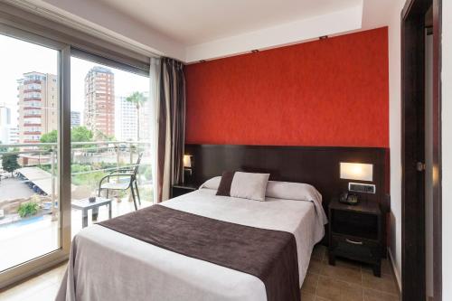 ベニドルムにあるSandos Monaco - Adults Onlyのベッドと大きな窓が備わるホテルルームです。