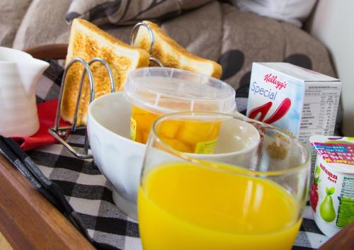 un tavolo con vassoio per la colazione con pane tostato e succo d'arancia di Bella Vista Motel Gisborne a Gisborne