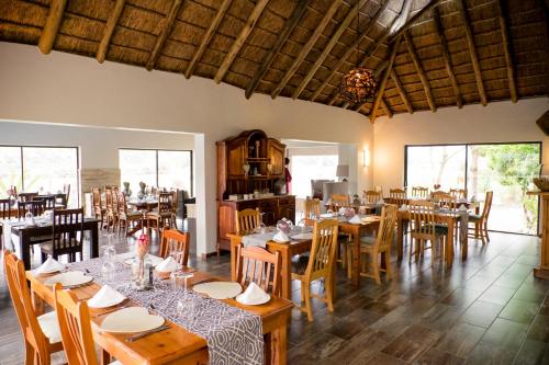 a restaurant with wooden tables and chairs and windows at De Old Drift Guest Farm in Addo