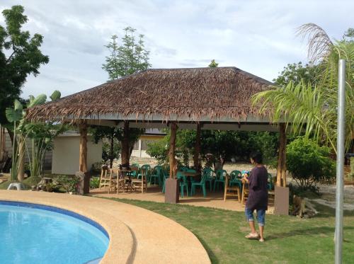 a person standing in front of a pavilion next to a pool at Adayo Cove Resort in Siquijor