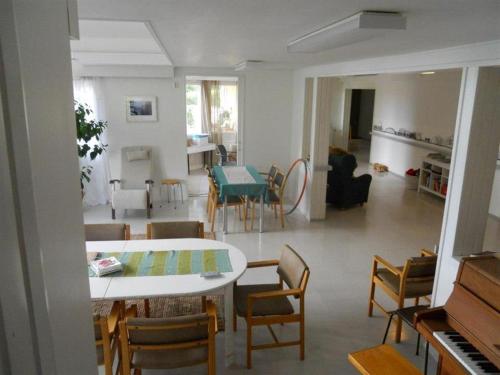 Majatalo Myötätuuli في Pitkäjärvi: غرفة معيشة مع طاولة وكراسي وبيانو