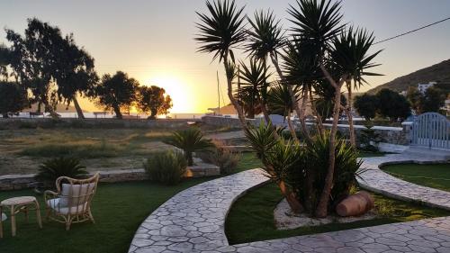 a garden with a palm tree and chairs and the sunset at Amorgos Pearls in Katapola