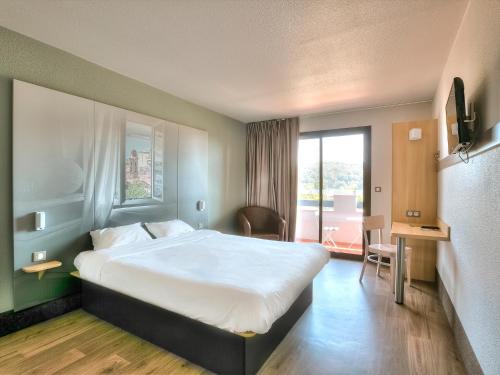 ヴィルヌーヴ・ルベにあるB&B HOTEL Villeneuve Loubet Villageの大きなベッドと窓が備わるホテルルームです。