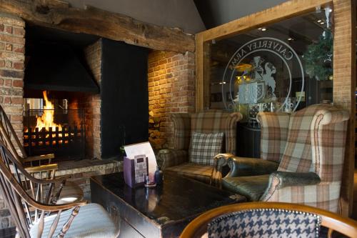 a living room with a fireplace and a couch and chairs at The Calverley Arms by Innkeeper's Collection in Pudsey