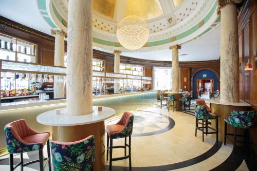 グラスゴーにあるvoco Grand Central Glasgow, an IHG Hotelのホテルのロビーにはバーと椅子があります。