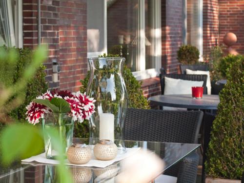 - une table en verre avec des vases et des fleurs sur la terrasse dans l'établissement Pension Landart, à Wangerland