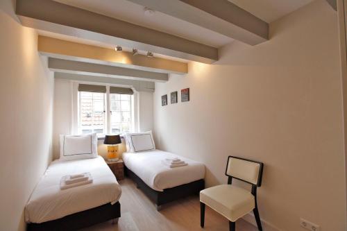 アムステルダムにあるResidences Canal Areaのベッド2台と椅子が備わる小さな客室です。