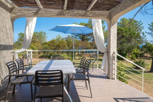 a patio with a table and chairs and an umbrella at Domaine de Pianiccia in Sari Solenzara
