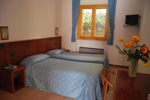 a bedroom with a bed and a table with a vase of flowers at Hotel Ristorante Il Gabbiano in Passignano sul Trasimeno