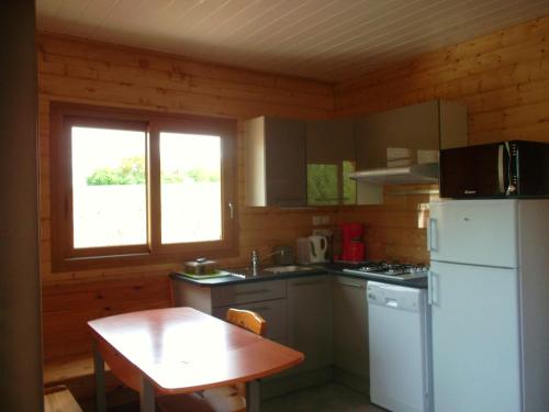 une cuisine avec une table et un réfrigérateur blanc dans l'établissement Chalet la Noisetiere Armalou, à Pouilly-sur-Loire