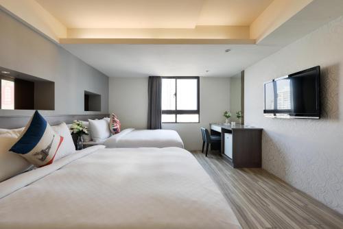 Habitación de hotel con 2 camas y escritorio en Taichung saint hotel en Taichung