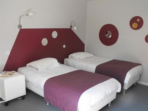 Pokój hotelowy z 2 łóżkami i czerwono-białą ścianą w obiekcie Logis Hôtel Restaurant Les Capucins w mieście Avallon