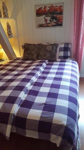 a bed with a blue and white checkered blanket at Egil's Vacation House in Lillehammer