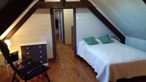1 dormitorio con 1 cama y 1 silla en el ático en Chez Maria, en Guerlédan