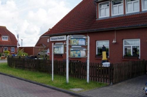 a gas pump in front of a red house at Gästehaus Restaurant Norddeich in Norddeich
