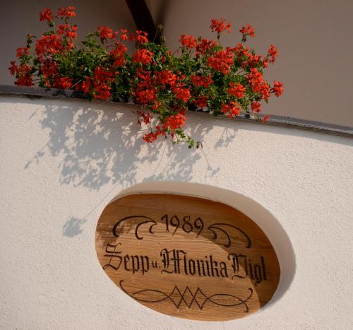 a sign on the side of a building with red flowers at Hotel Lengsteinerhof in Longomoso