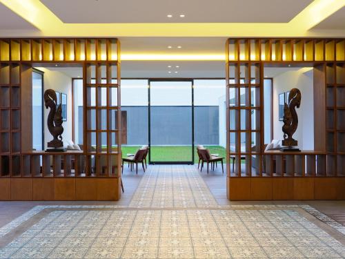 a lobby with chairs and tables and glass doors at The Bale Phnom Penh by LifestyleRetreats in Phnom Penh