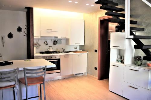 a kitchen with white cabinets and a table with chairs at Appartamento Via Mazzini in Rovigo