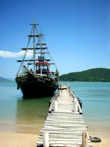 a boat sitting on the water next to a dock at Fragata Apart Hotel in Florianópolis