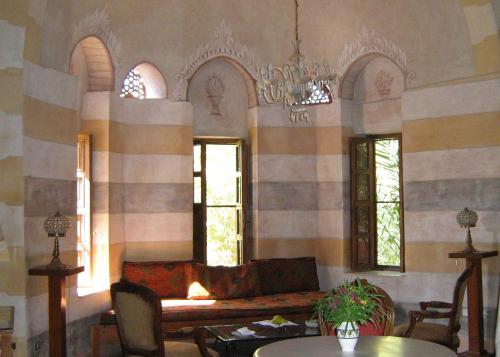 a living room with a couch and two windows at Al Moudira Hotel in Luxor