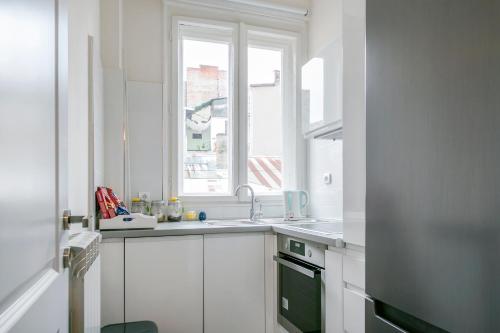 cocina blanca con fregadero y ventana en Urban Downtown Apartment en Belgrado