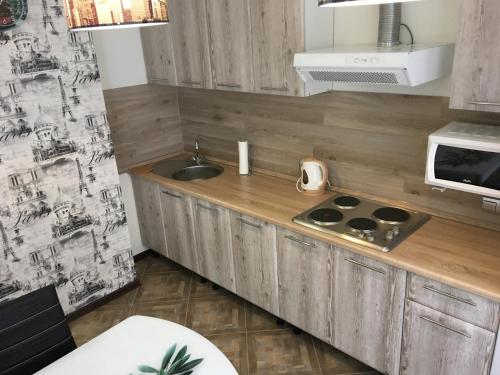 a small kitchen with a sink and a microwave at Apartament Berloga55 on 10 Let Oktiabria in Omsk