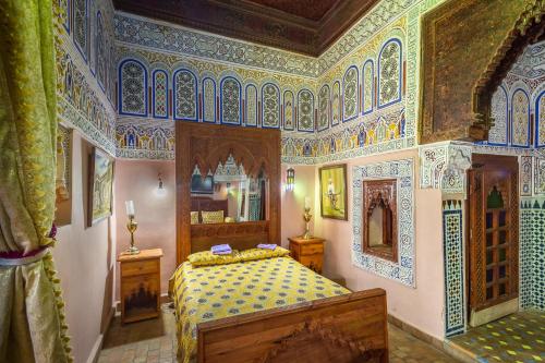 a bedroom with a bed in a room with colorful ceilings at Riad Hiba in Meknès