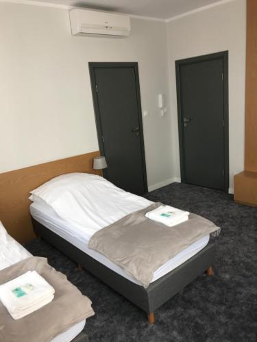 a bedroom with two beds and two black doors at 7 Rooms MTP in Poznań