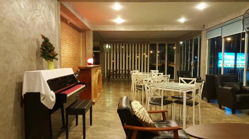 un restaurante con piano, mesas y sillas en Baan Sanpoom, en Phitsanulok